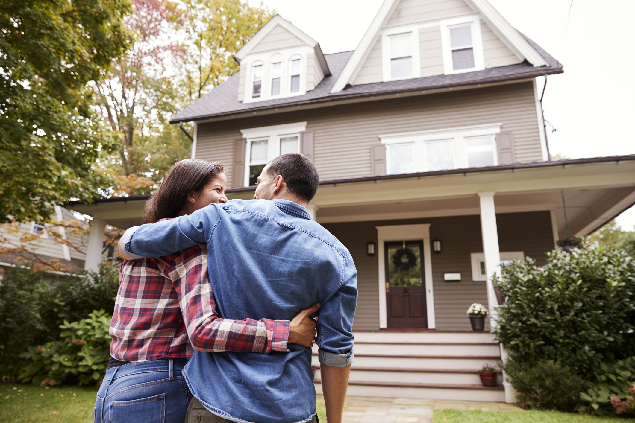 A loving couple walking toward their home that was fully remodeled after a house fire thanks to the large settlement that they received from hiring Fire Loss Consultants.
